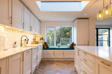 Kitchen with rooflight, fitted cabinetry, central island and window seat.