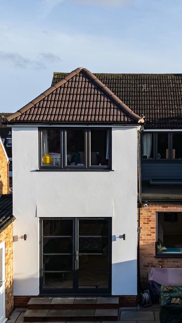 Finished two-storey rear extension with white render and black-framed glazing.