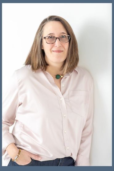 Author Erica Colahan standing against a white wall.
