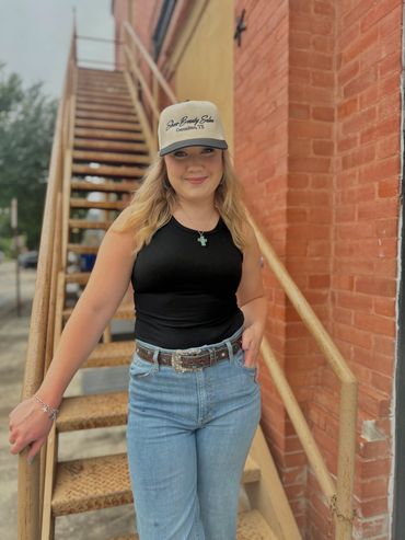 Young woman in casual outfit posing by outdoor metal stairs and brick wall.