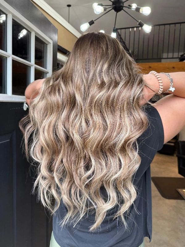 Long wavy hair with blonde highlights styled beautifully indoors.