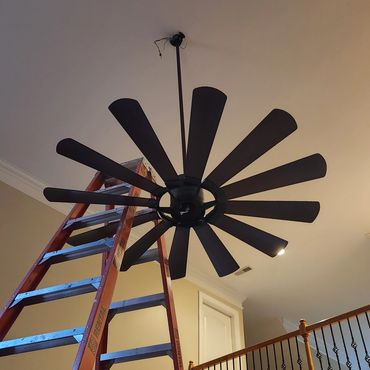 Ladder positioned under a ceiling fan being installed.