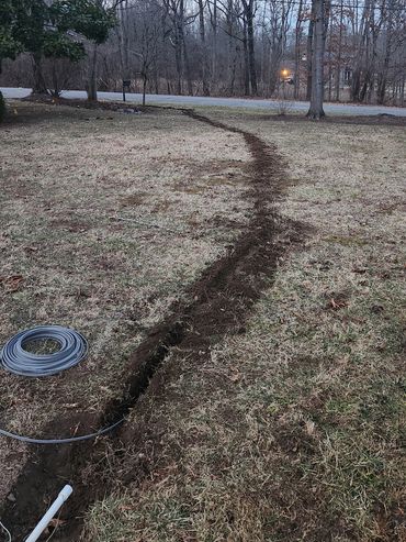 Trench with cable rolling in yard.