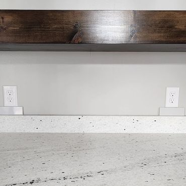 Clean kitchen countertop with a floating wooden shelf above.
