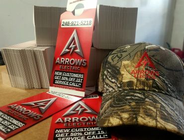 Promotional items for Arrows Electric including door hangers and a camo hat.