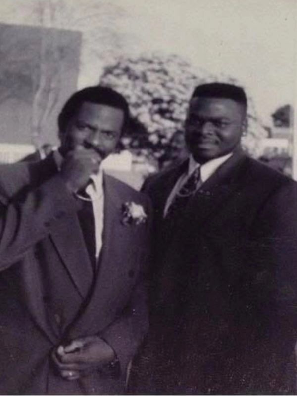 Two men dressed in formal suits posing for a photo.