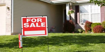 A house with a for sale sign in the front yard