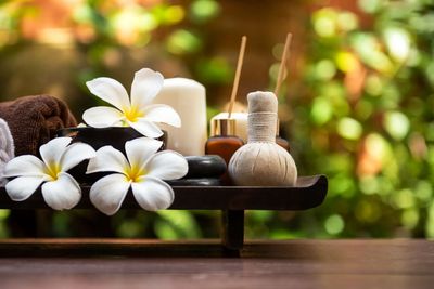 Spa essentials with white flowers and candles on wooden tray.