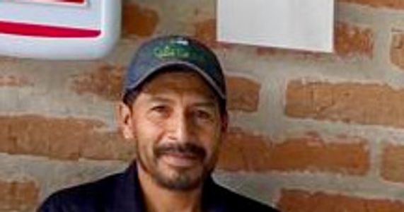 Man in casual outfit sitting against a brick wall.