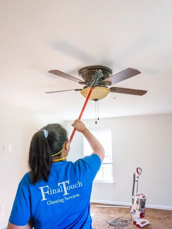 A woman cleaning a ceiling fan