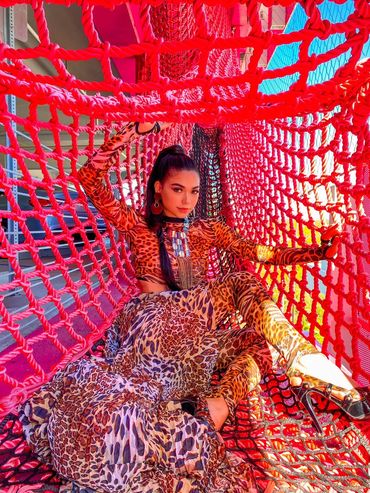 Woman in leopard print outfit posing inside a vibrant red net structure.