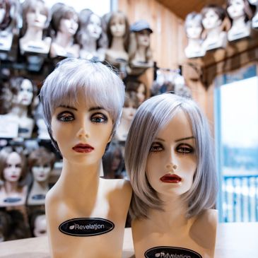 Two mannequin heads with silver wigs in a wig shop.