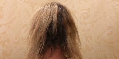 Person with long, messy hair facing a patterned wall.