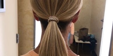 Blonde hair tied in a low ponytail with a decorative hair tie.