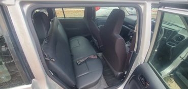 Backseat view of a car interior with black seats and open doors.