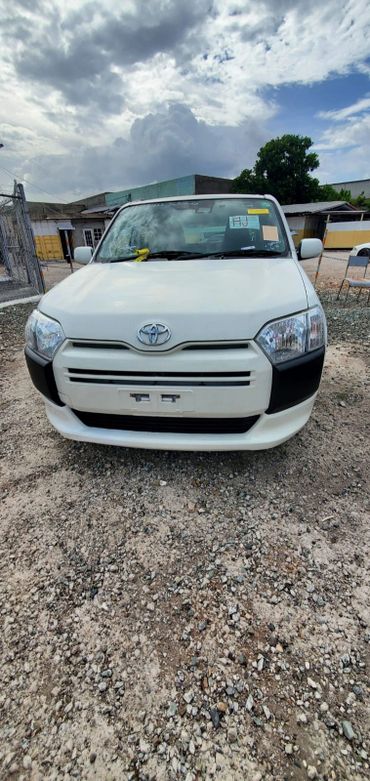 Front view of a white Toyota car parked on a gravel surface.