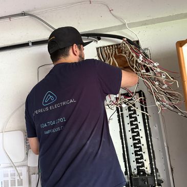 Electrician working on a complex wiring panel with many cables.