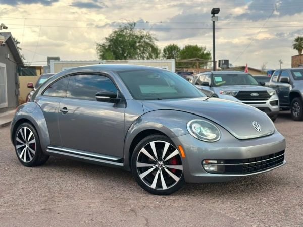 Gray Volkswagen Beetle parked outdoors on a cloudy day.