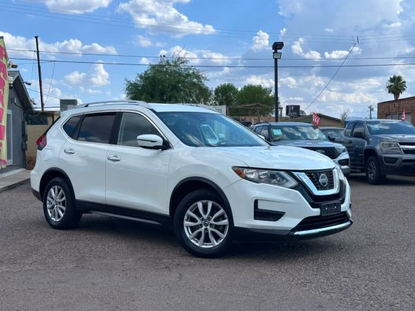 White Nissan SUV parked outdoors under a blue sky.