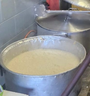 Large metal pot filled with a creamy, bubbling substance in a kitchen.
