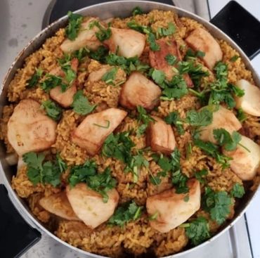 A pot of cooked spiced rice garnished with fried plantains and fresh cilantro.