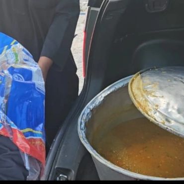 Large pot of food being transported in a vehicle trunk.