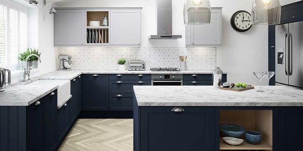 Modern kitchen with navy blue cabinets and marble countertops under natural light.