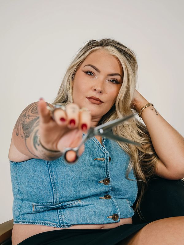 Confident woman holding scissors towards the camera.