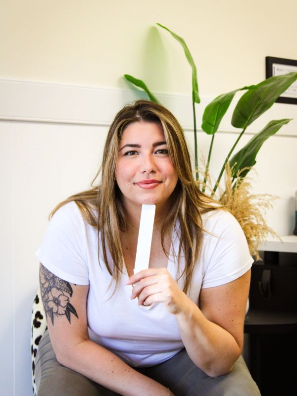 Woman with tattoo holding a white strip and smiling.