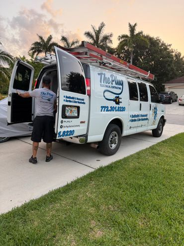 Electrician opening a van door with The Plug Electrical Contracting branding.