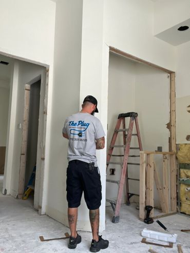 Electrician working in a construction site with tools and ladder.