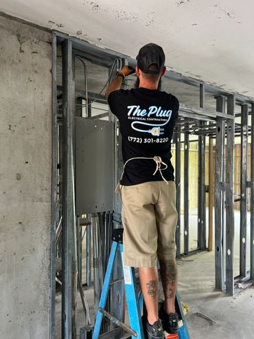 Electrician working on wiring inside a building under construction.