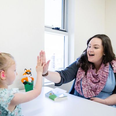 Young girl giving high 5 to her speech pathologist