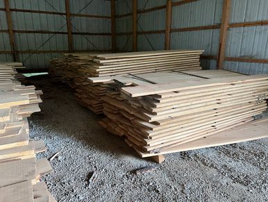 Large stacks of milled hardwood boards inside a pole barn.  Kiln dried by Clayton Meadow.