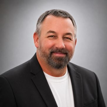 Smiling man in black blazer and white shirt.