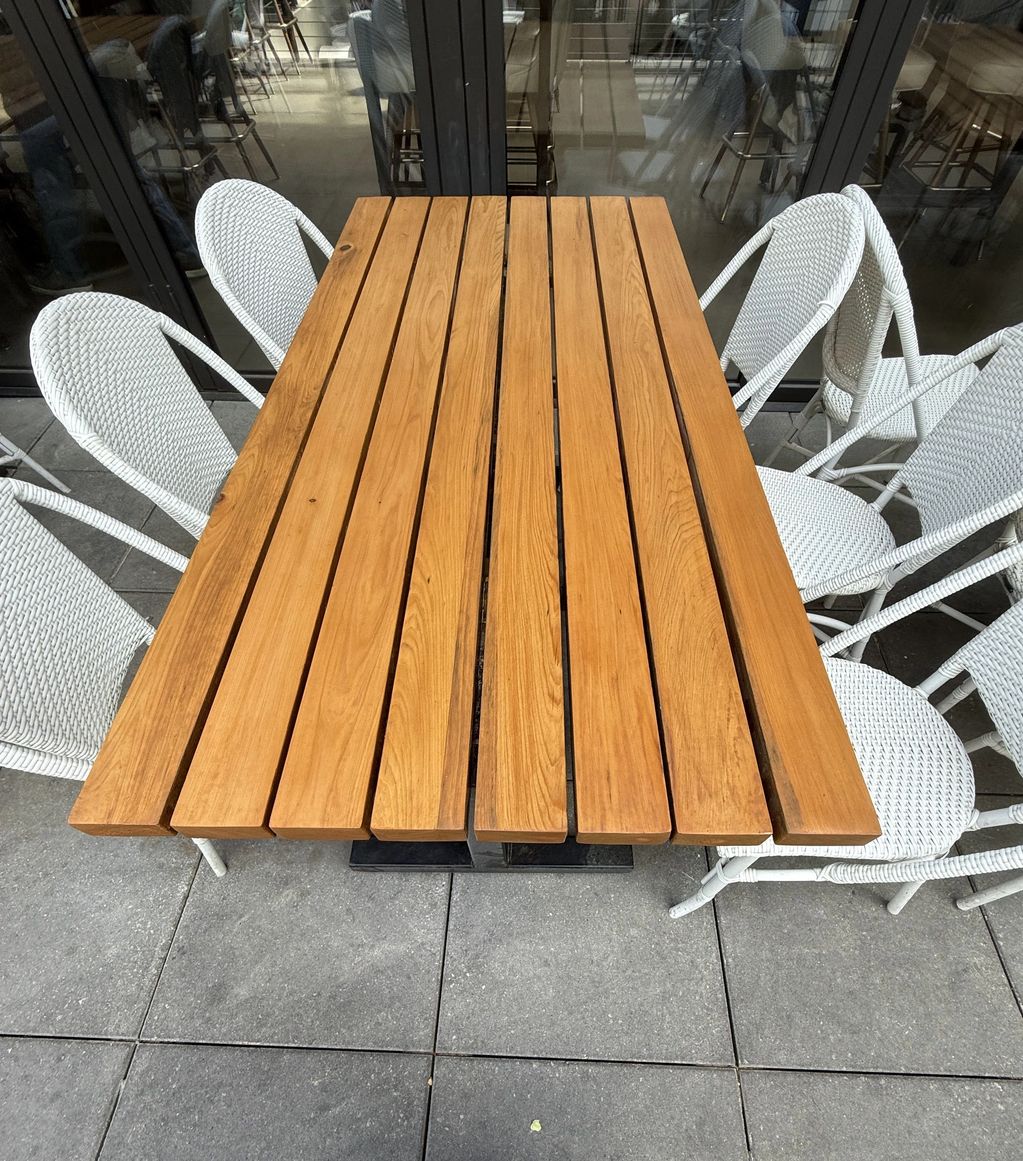 Wooden table with six white chairs on a patio.