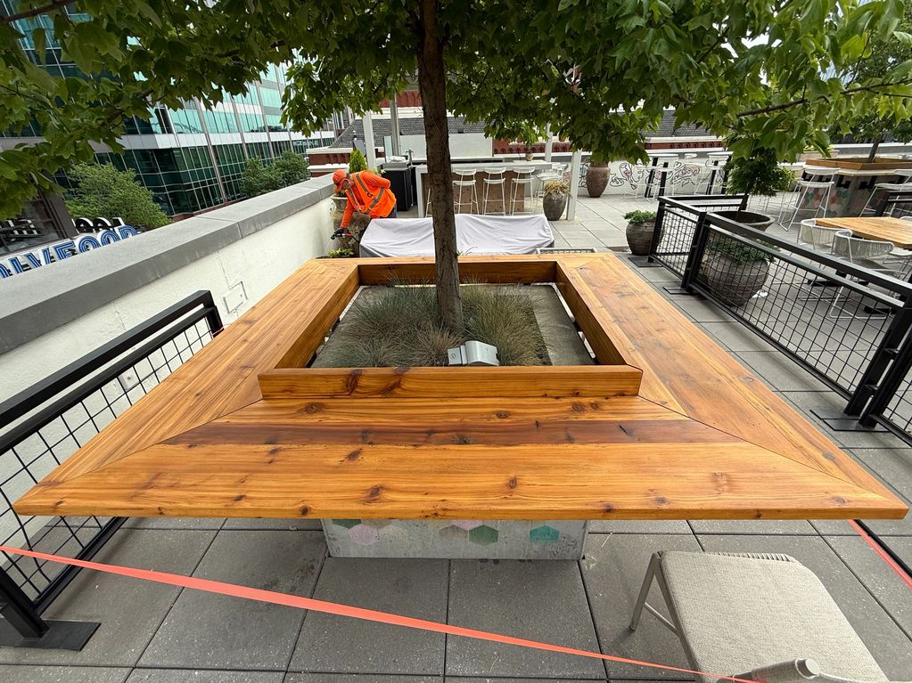 Wooden bench surrounding a tree on a terrace.