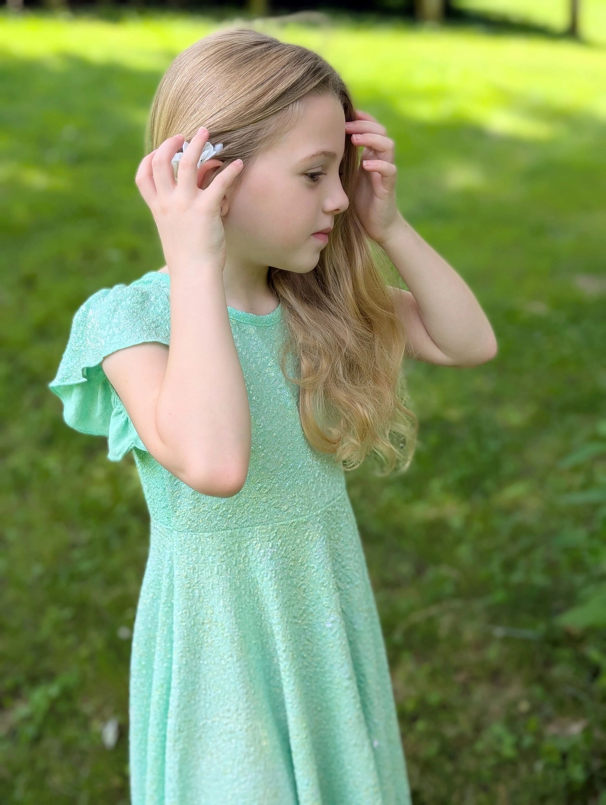Young blond haired girl in light green dress with daisy in her hair
