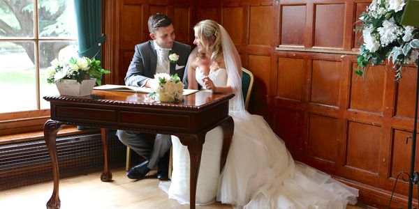 bride and groom signing wedding registrar