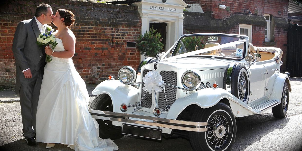 couple kissing in front of vintage Beauford wedding car