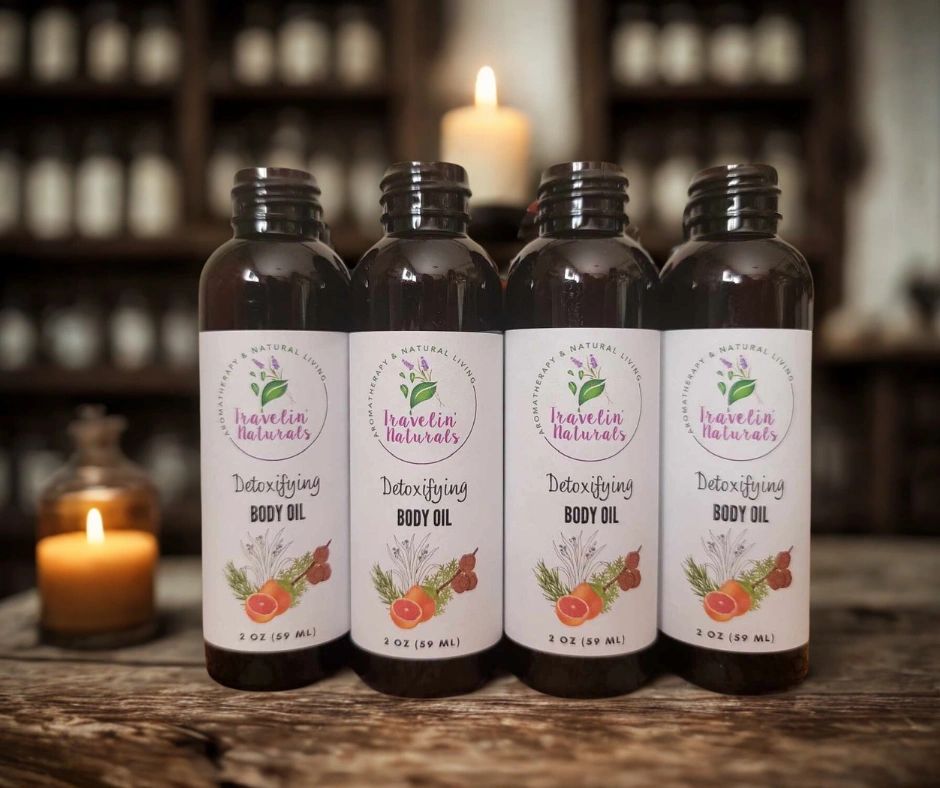 Four bottles of detoxifying body oil on a wooden surface with candles in the background.