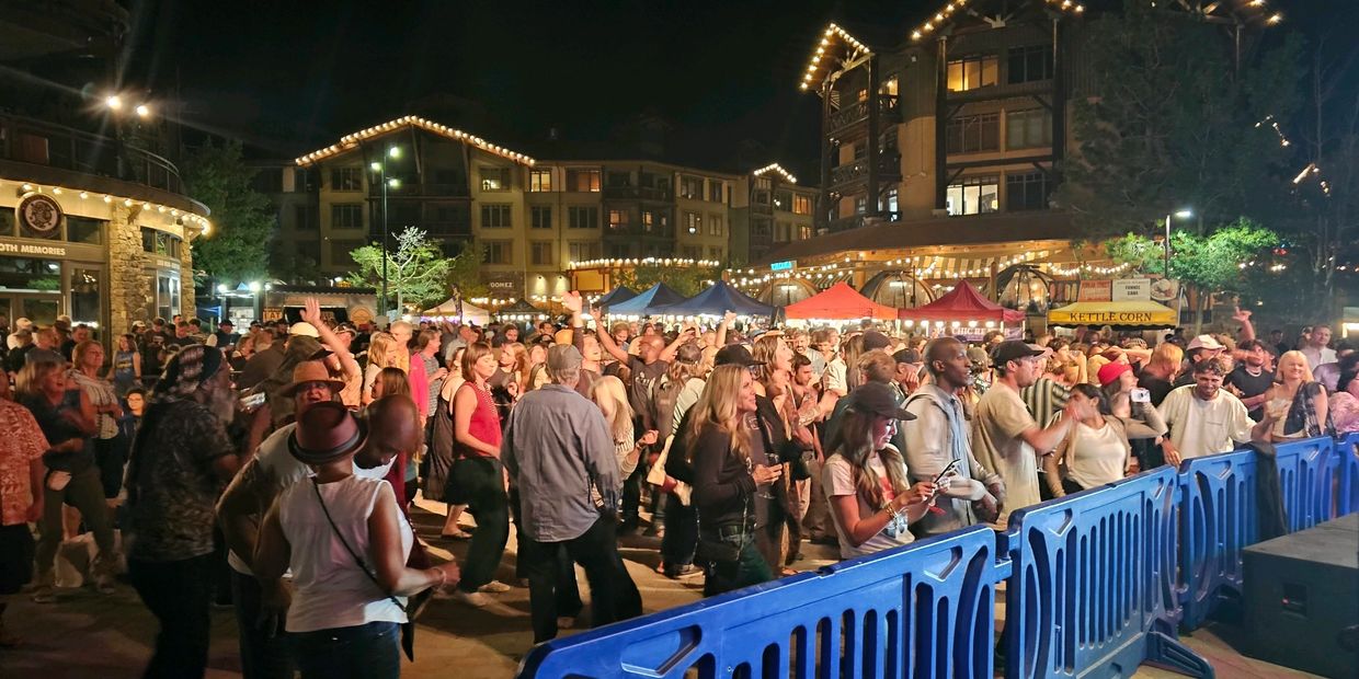 Crowd enjoying a lively night event with illuminated buildings and booths.