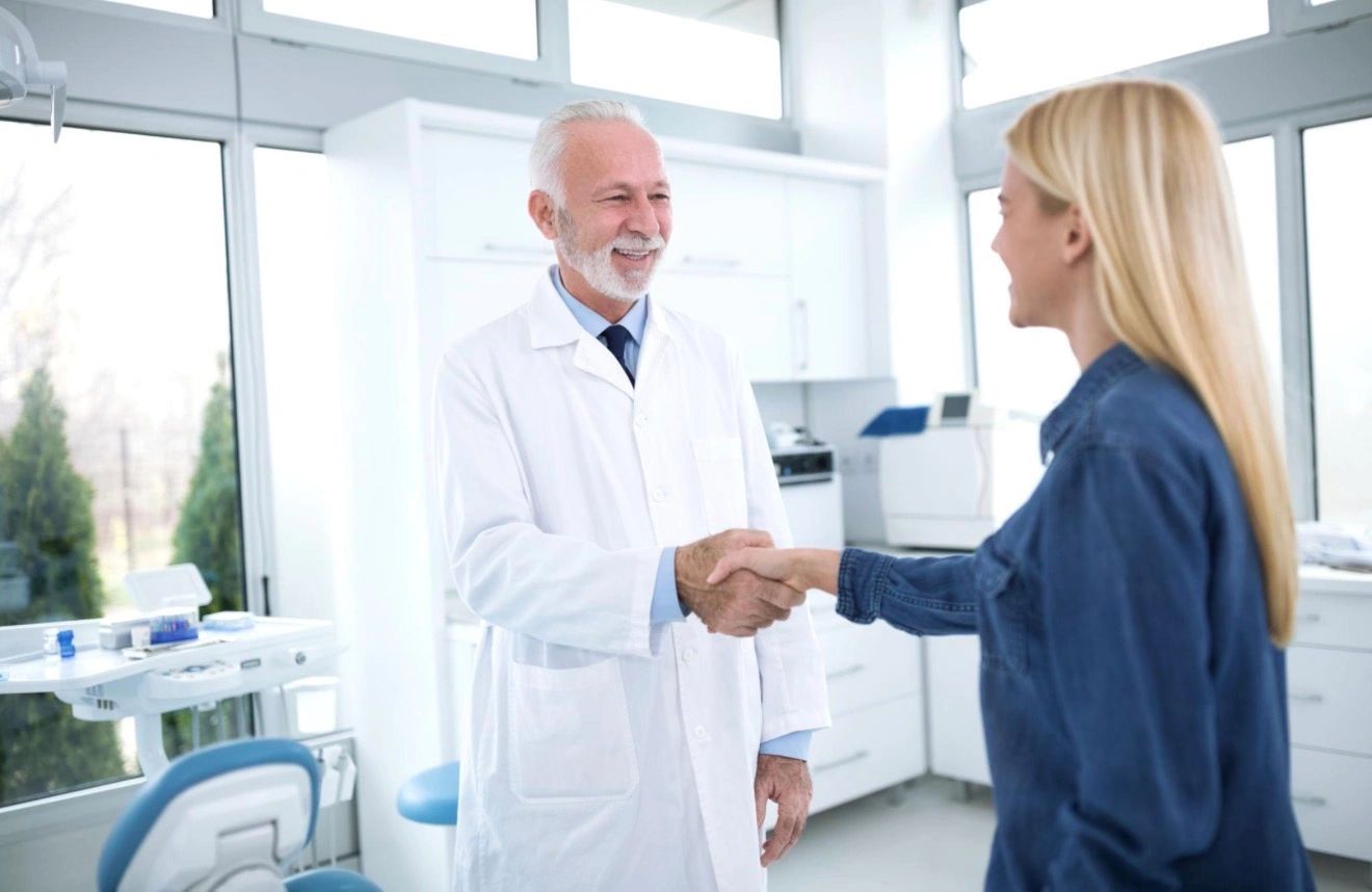 Doctor and patient shaking hands in a bright medical office.