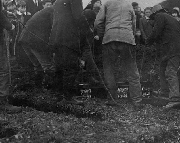 A group of people burying a coffin.