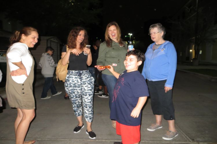 A group of people using ghost hunting equipment and smiling on the ghost tour.