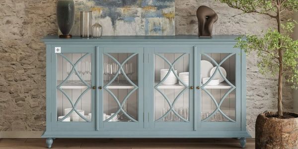 Blue cabinet with glass doors, decorative items, and a green plant against a stone wall.