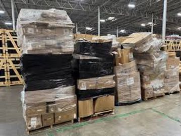 Stacked pallets of various boxes wrapped in plastic in a warehouse.