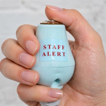 Hand holding a blue alert device labeled 'STAFF ALERT'.