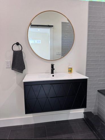 Modern bathroom sink with black vanity and round mirror.