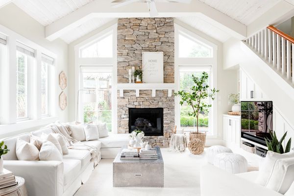 Interior design vaulted living room with stone fireplace and white furniture white ship lap ceiling